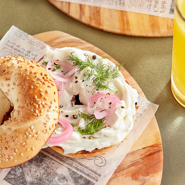 A bagel with Daiya vegan cream cheese and onions on a wooden plate.