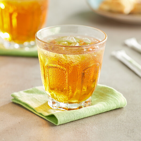 A glass of Old Orchard apple juice with ice on a table
