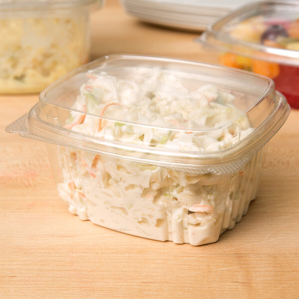 A Genpak clear plastic deli container with coleslaw inside and a high dome lid.