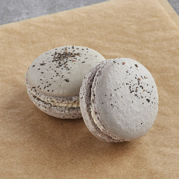 Two Earl Grey macarons on a brown paper bag.