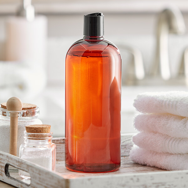 A Boston round amber plastic bottle of liquid on a tray with towels.