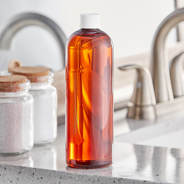 A Boston Round 16 oz. amber plastic bottle of liquid on a counter.