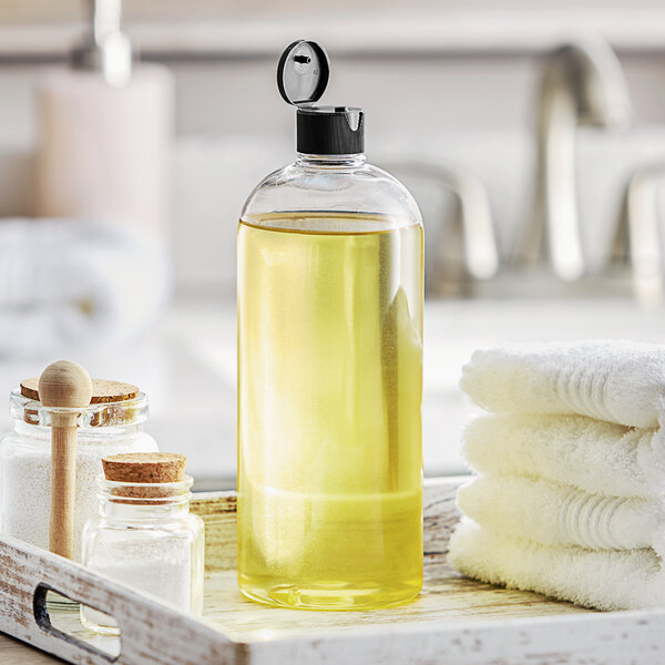 A Boston round clear plastic bottle with a black flip top lid on a tray with towels.