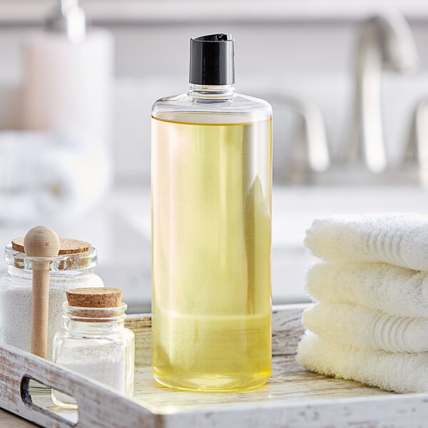 A clear cylindrical plastic bottle with black disc top lid sits on a tray with towels.