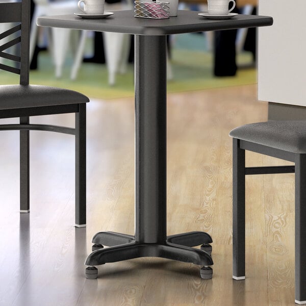 A black Lancaster Table & Seating column table base on a wooden table.