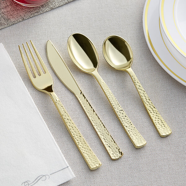 A Visions Hammersmith gold flatware set with gold spoons and a fork on a table.
