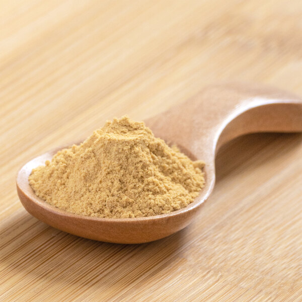 A spoonful of Grapefruit Peel Powder on a wooden table.