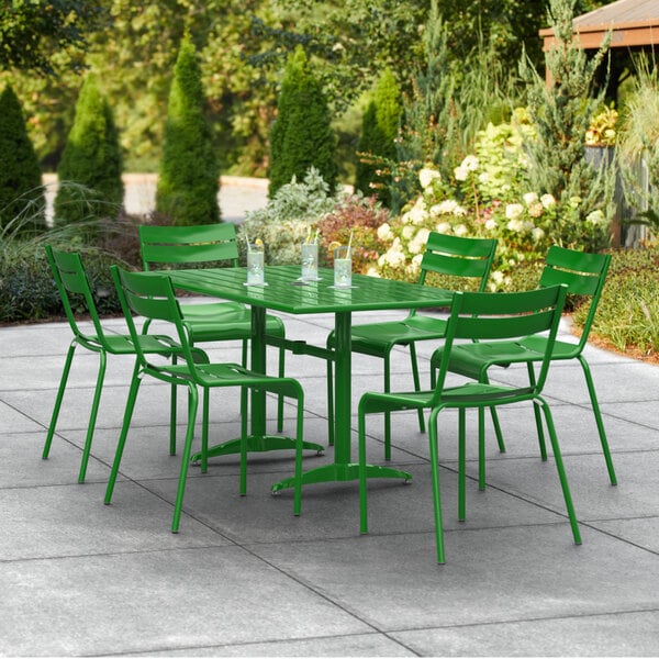 A green Lancaster Table & Seating outdoor table with chairs on a patio.