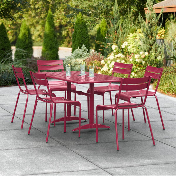 A Lancaster Table & Seating sangria powder-coated aluminum table with chairs on a patio.