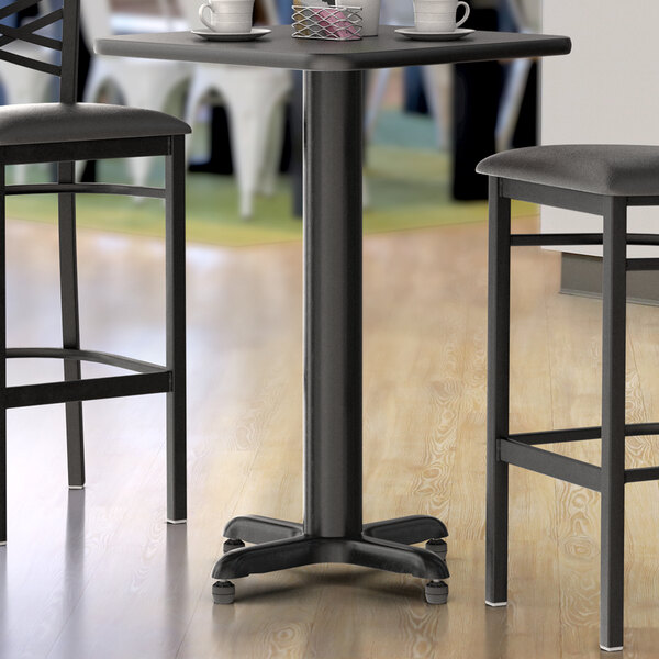 A Lancaster Table & Seating black counter height table base on a table with two chairs.