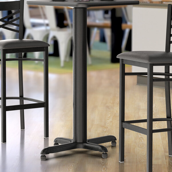 A Lancaster Table & Seating black bar table base on a table with bar stools.