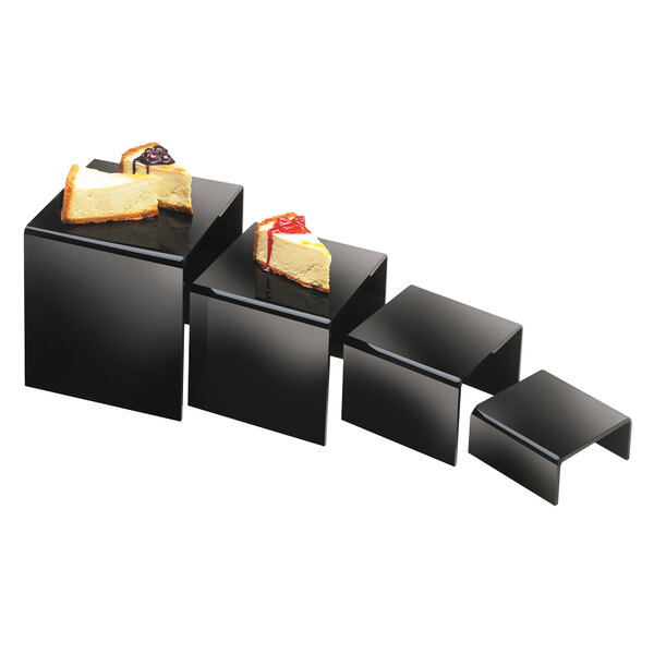 A black rectangular Cal-Mil nesting riser set with slices of cheesecake on it.