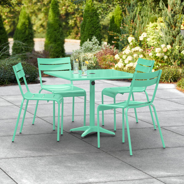 A Lancaster Table & Seating seafoam green table with 4 chairs on a patio.