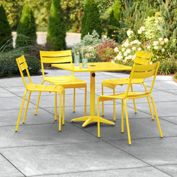 A yellow table and chairs on an outdoor patio.