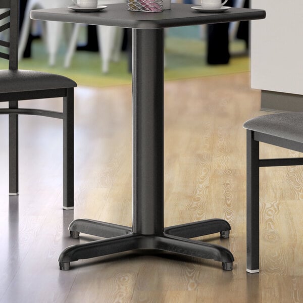 A black Lancaster Table & Seating table base with a wooden surface.