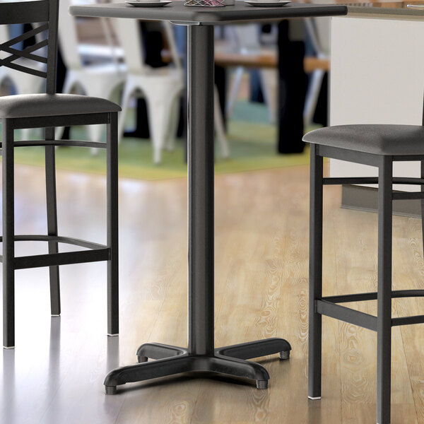 A Lancaster Table & Seating black metal bar table base with leveling feet.
