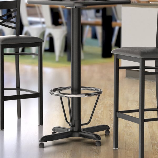 A black Lancaster Table & Seating bar table base with a foot ring.