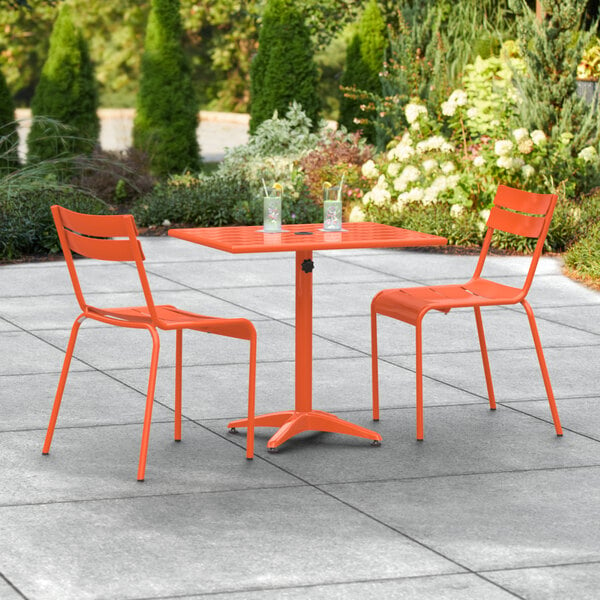 An orange table and two chairs on an outdoor patio.