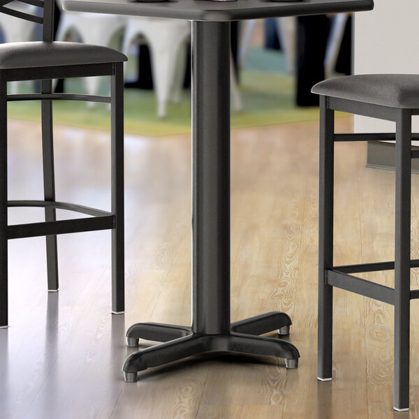A close-up of a Lancaster Table & Seating black metal counter height table base with leveling feet.