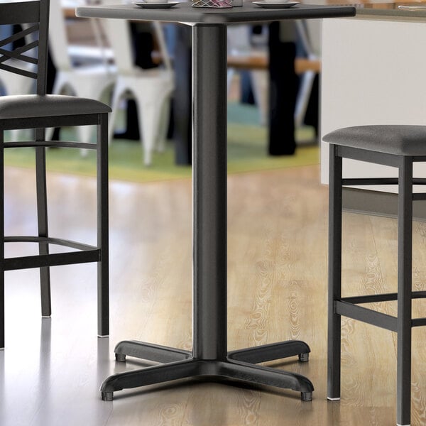 A close-up of a black Lancaster Table & Seating bar height table base with leveling feet.
