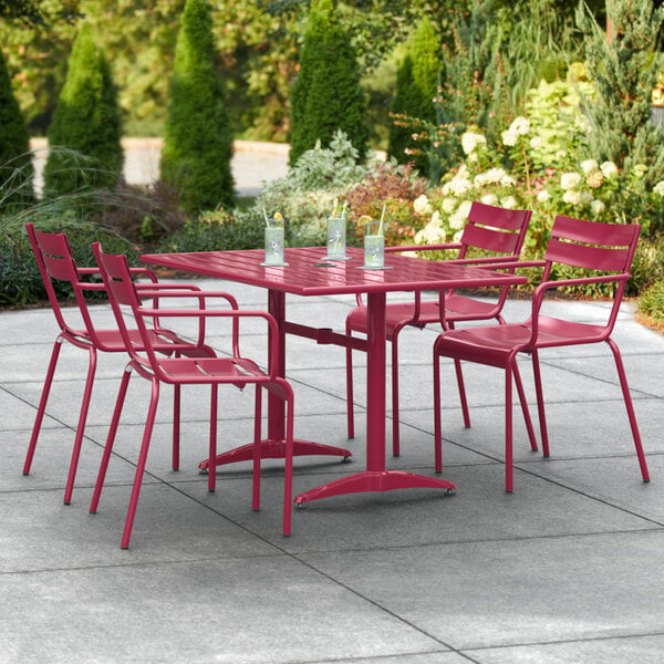 A red table with chairs on an outdoor patio.