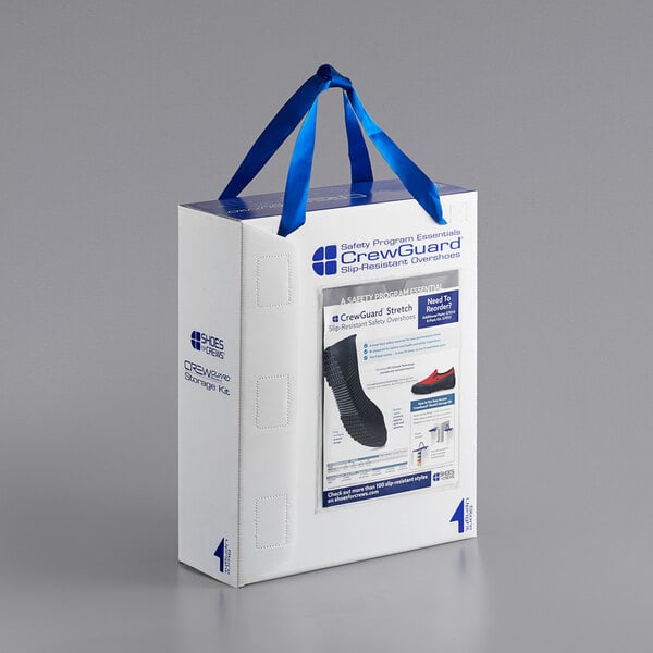 A white box with a blue ribbon and blue and black Shoes For Crews CrewGuard overshoes.