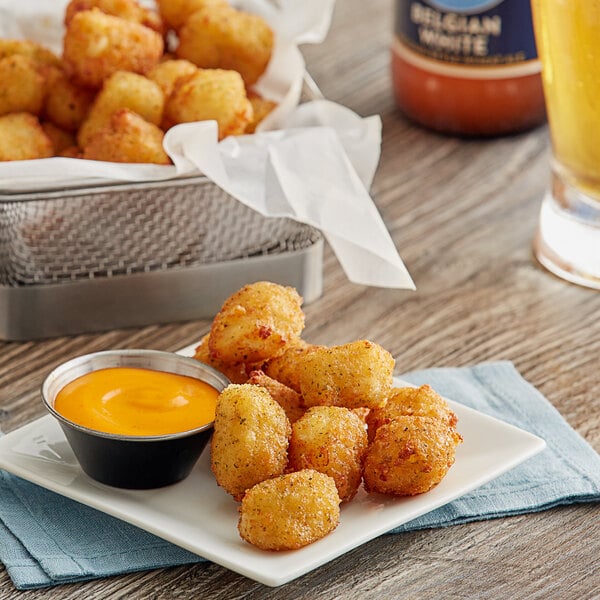A plate of Fred's Breaded Ranch Cheese Curds with sauce on a table.
