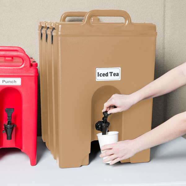 A person pouring a drink into a Cambro insulated beverage dispenser.