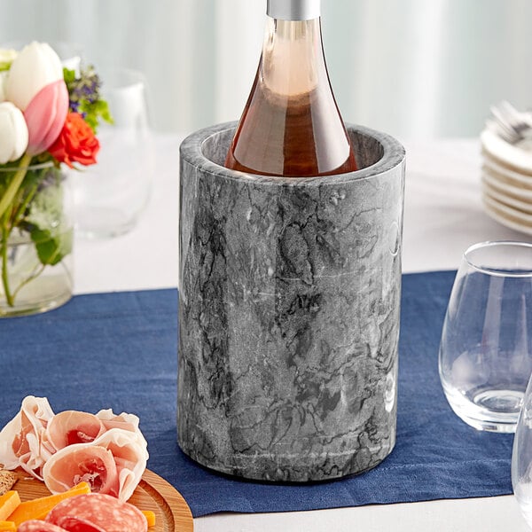 A bottle of wine in a black marble wine cooler.