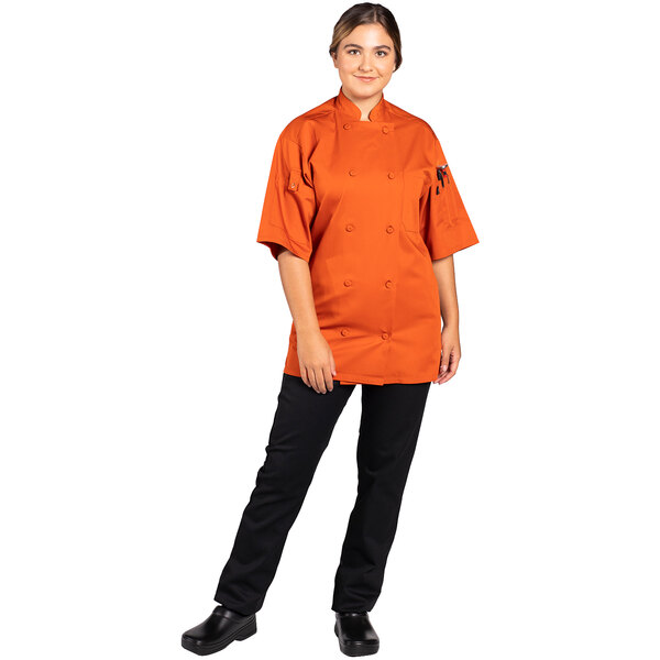 A woman wearing an orange Uncommon Chef short sleeve chef coat.