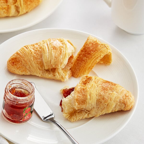 A plate with two White Toque Butter Croissants and strawberry jam on the side.