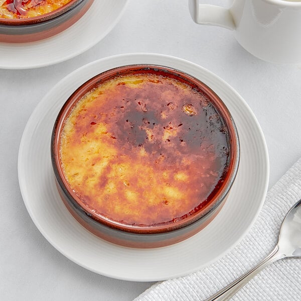 A bowl of White Toque Creme Brulee on a white plate with a spoon.