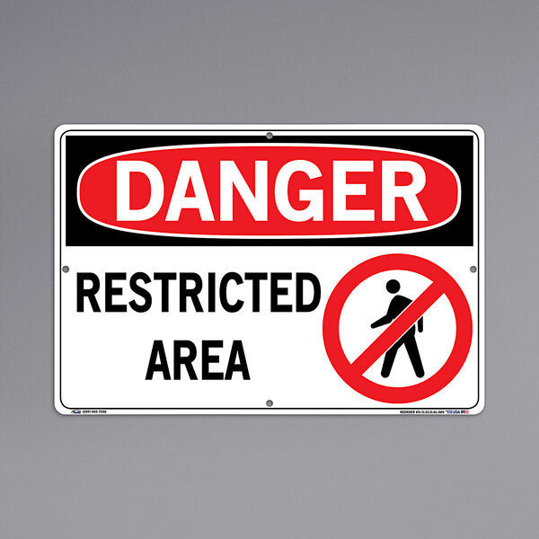 A white and aluminum rectangular sign that says "Danger / Restricted Area" on a wall.