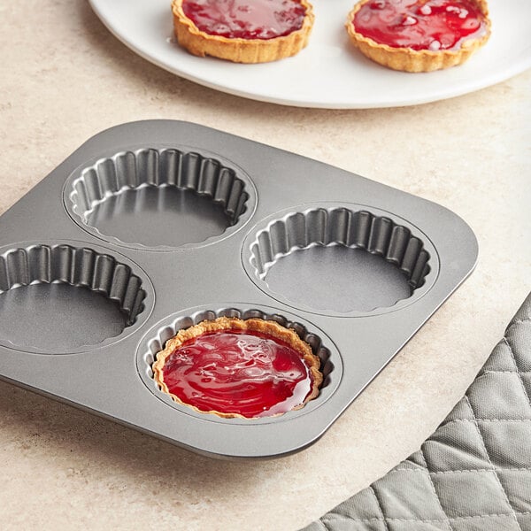 A Baker's Mark fluted tartlet pan filled with tarts, each with red jelly in the center.