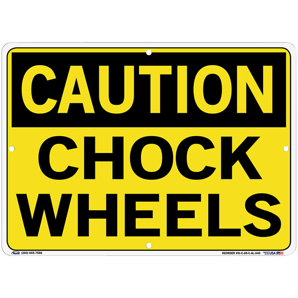 A yellow sign with black text that says "Caution / Chock Wheels" over a white background.