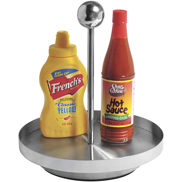 A GET stainless steel Lazy Susan condiment caddy with a ketchup bottle and a bottle of hot sauce.