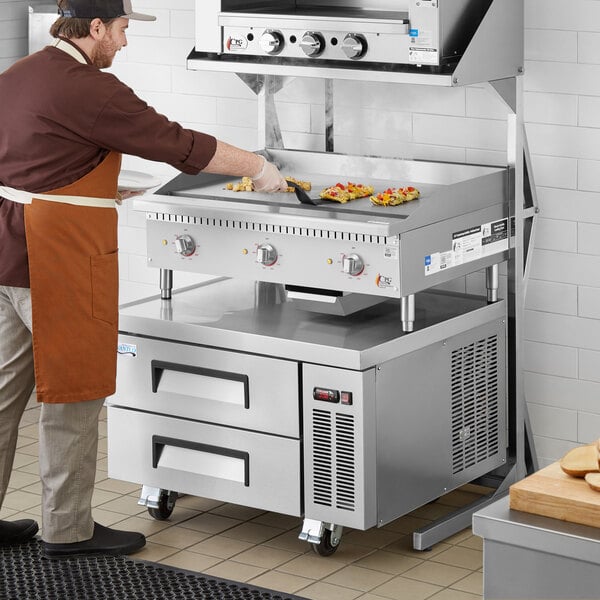 A man in an apron using a Cooking Performance Group electric countertop griddle.