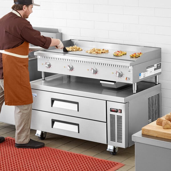 A man wearing an apron cooking on a Cooking Performance Group electric countertop griddle.