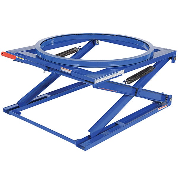 A blue scissor lift with a circular handle on a table.