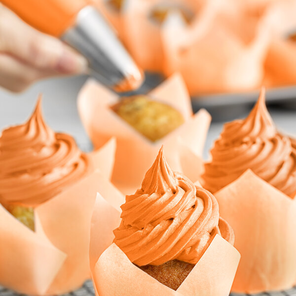 A close-up of cupcakes with orange frosting swirled on top.