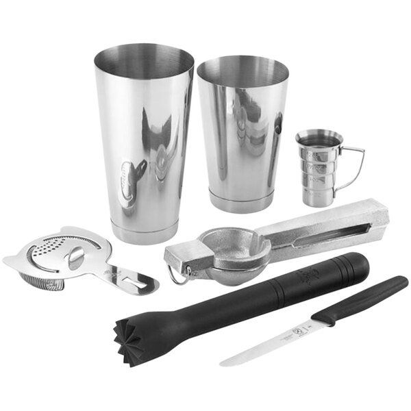 A Barfly stainless steel cocktail tool set on a counter with a cocktail shaker, knife, and other tools.