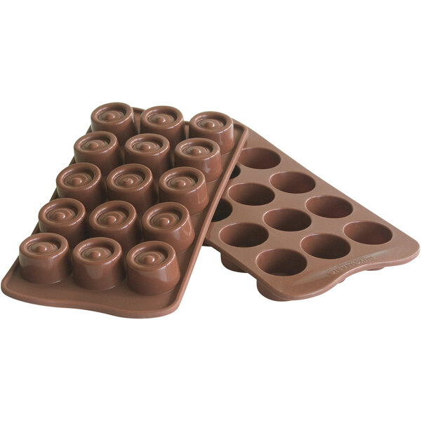 A Silikomart brown silicone chocolate mold with 15 compartments on a counter filled with chocolates.