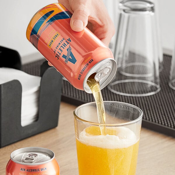 A hand pouring Athletic Brewing Co. Free Wave Non-Alcoholic Hazy IPA from a can into a glass.