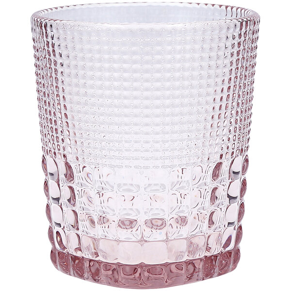 A close up of a Fortessa Malcolm pink rocks glass with a patterned design and a pink rim.