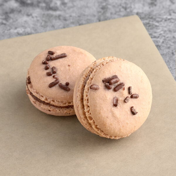 Two Macaron Centrale Dutch Chocolate Buttercream macarons on a brown paper.