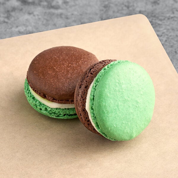 Two white and green Macaron Centrale macarons on a table.