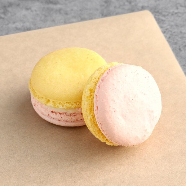A pink and yellow Macaron Centrale gummi bear macaron on brown paper.
