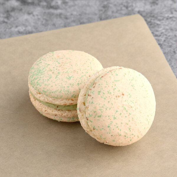 Two Jasmine Macarons with green and white sprinkles.