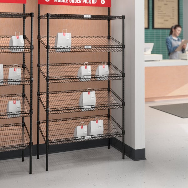 A Regency black epoxy NSF shelving station with slanted drop in baskets on a shelf with a PVC overlay.