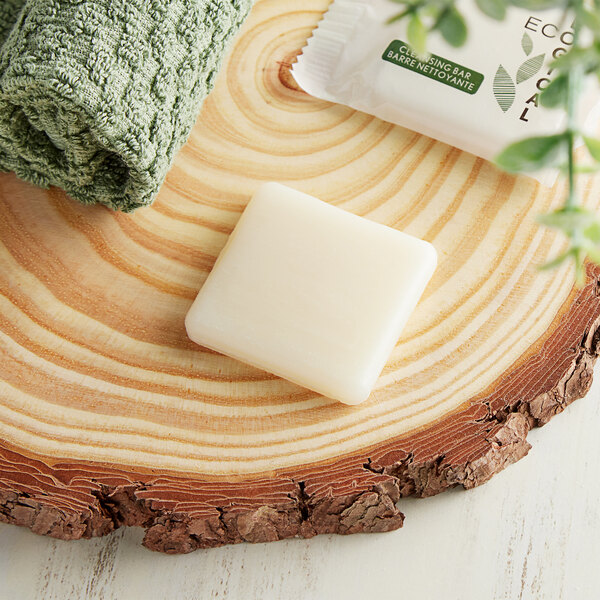A towel and a piece of EcoLOGICAL bar soap on a wood surface.